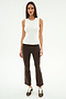 A woman faces forward against a white background, wearing the SPLITS59 Carter Airweight Lite Tank in white, paired with brown flared spandex pants with side stripes and brown sneakers.