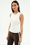 A woman models the SPLITS59 Carter Airweight Lite Tank in white with brown spandex leggings featuring a white side stripe, standing against a plain white background.