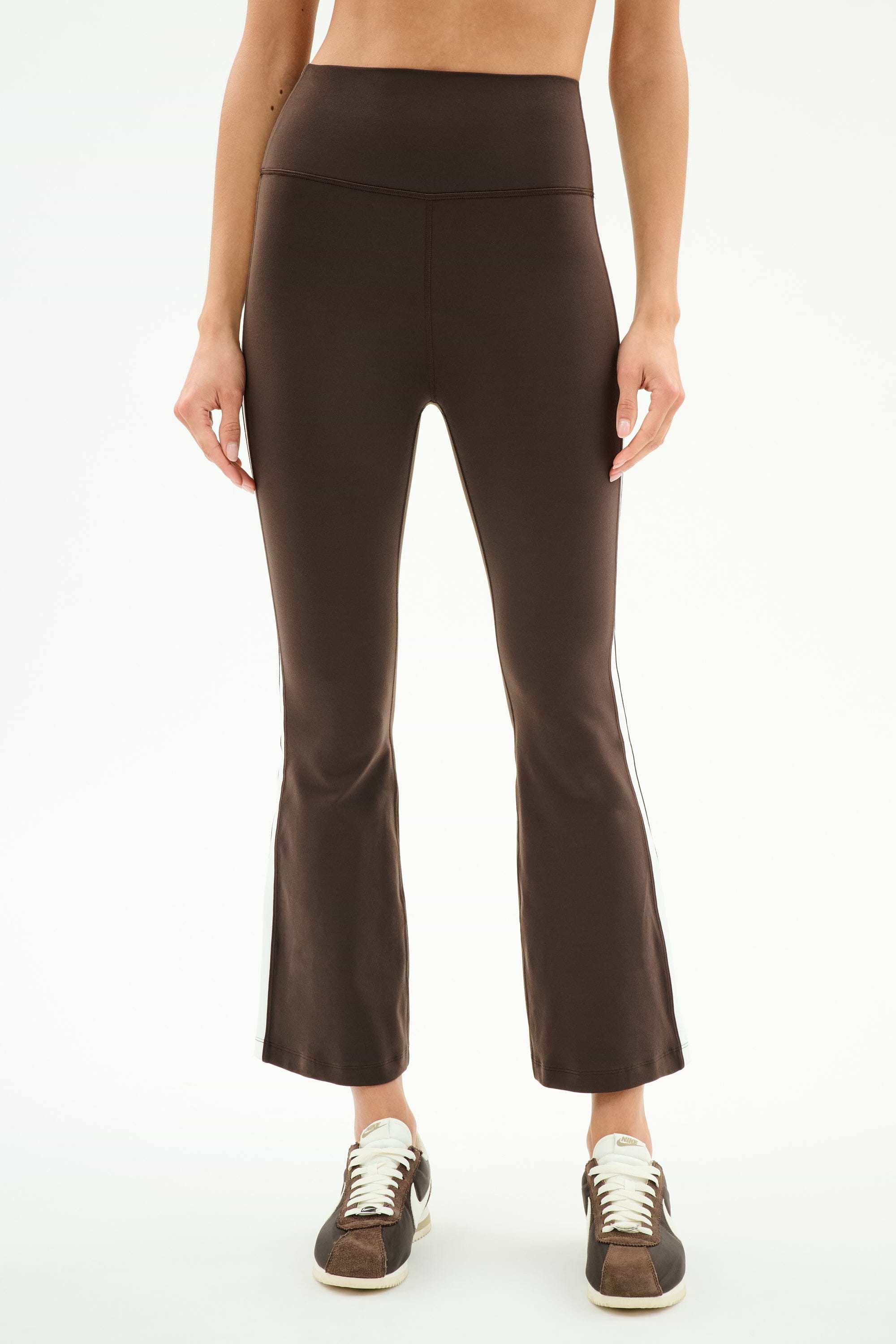 Model wears SPLITS59 Raquel High Waist Supplex Crop in Dark Chocolate/White with brown sneakers, shown from shoulders down against a plain white background.