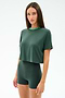 A woman stands against a plain background wearing the SPLITS59 Djuna Crop Ringer in Military/Spearmint, a dark green cropped t-shirt made from a soft viscose and elastane blend.