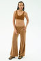 A person stands against a plain white background wearing SPLITS59’s Joy Velour Pant in Honey, crafted from soft polyester spandex fabric, paired with a matching brown crop top and colorful sneakers.
