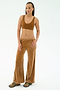 A woman stands against a plain background wearing the SPLITS59 Joy Velour Pant in Honey, a brown polyester spandex sports bra, and multicolored sneakers.