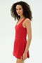 A woman with curly hair models the SPLITS59 Martina Rigor Dress in Pirate Red, sleeveless, standing against a plain white background and facing slightly to the side.