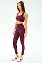 A woman faces left wearing SPLITS59 Airweight Super High Waist 7/8 leggings in Dark Cherry with a matching sports bra, ideal for hot yoga, paired with white athletic shoes against a plain white background.
