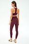 A woman faces away wearing SPLITS59’s Airweight Super High Waist 7/8 leggings in Dark Cherry with a matching sports bra and maroon-striped white sneakers, set against a plain white background—ideal for hot yoga or daily wear.