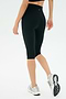 A person in SPLITS59 Airweight High Waist 16" Legging - Black, a black top, and white running shoes stands against a plain white background.