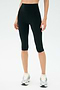 A person wears SPLITS59 Airweight High Waist 16" Legging in black with white running shoes, standing against a plain light background.