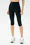 A person wears SPLITS59 Airweight High Waist 16" Legging in black with white running shoes, standing against a plain light background.