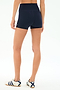 A person stands on a plain background wearing SPLITS59 Airweight High Waist 3.5” Short in Indigo, paired with white sneakers with navy stripes—an ideal look for Pilates.