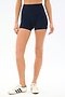 A person wears SPLITS59 Airweight High Waist 3.5” Short in Indigo and white sneakers with blue stripes, standing against a plain white background—ideal for Pilates or hot yoga sessions.