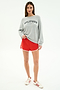 A woman faces forward in a heather grey SPLITS59 Andie Oversized Fleece Varsity Graphic Sweatshirt with "Los Angeles" text—casually stylish, by SPLITS59.