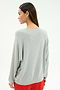 A woman stands with her back to the camera wearing the SPLITS59 Andie Oversized Fleece Varsity Graphic Sweatshirt in Heather Grey, paired with red shorts, set against a plain light background.