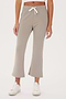 Woman wearing SPLITS59 Brooks Fleece Cropped Flare - Latte pants and white sneakers, standing against a plain background.