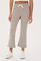 Woman wearing SPLITS59 Brooks Fleece Cropped Flare - Latte pants and white sneakers, standing against a plain background.