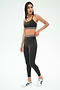 A woman wears the SPLITS59 Cali Active Rib Bra in Heather Graphite with matching high-waisted leggings featuring white stripe accents and white sneakers, standing against a plain light background.