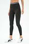 A person wears the SPLITS59 Bailey Active Rib High Waist 7/8 leggings in Heather Graphite, featuring a white striped waistband and white sneakers, standing against a plain background—ideal for gym workouts or casual wear.