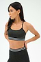 A woman in the SPLITS59 Cali Active Rib Bra in Heather Graphite stands with hands behind her back, looking left, wearing matching high-waisted leggings with white and black stripes.