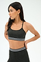 A woman in the SPLITS59 Cali Active Rib Bra in Heather Graphite stands with hands behind her back, looking left, wearing matching high-waisted leggings with white and black stripes.