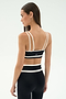 A woman stands in profile against a plain light background, wearing the SPLITS59 Eva Rigor Double Strap Bra in black/white and black leggings, her hair straight and loose—ready for running or gym workouts.