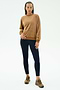 A person wears the SPLITS59 Joy Velour Crewneck in Honey, paired with black leggings and brown sneakers, standing against a plain white background.
