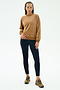 A person wears the SPLITS59 Joy Velour Crewneck in Honey, paired with black leggings and brown sneakers, standing against a plain white background.