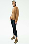 A person stands against a plain background wearing the SPLITS59 Joy Velour Crewneck in Honey, paired with black side-stripe leggings and brown athletic shoes.