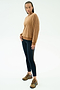 A person stands against a plain background wearing the SPLITS59 Joy Velour Crewneck in Honey, paired with black side-stripe leggings and brown athletic shoes.