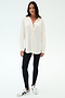 A woman stands against a white background wearing the SPLITS59 Kate Airweight Lite Button Down in white, styled as a chic layering piece with black leggings and white sneakers featuring black stripes.