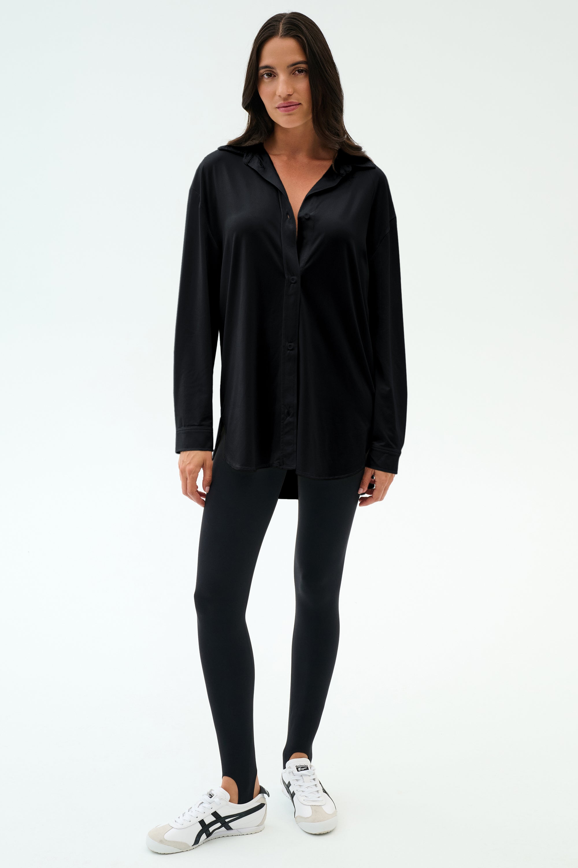 A person stands against a plain white background wearing the SPLITS59 Kate Airweight Lite Button Down in black—styled with black leggings and white sneakers with black details for a chic, versatile look.