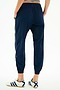 A person models the SPLITS59 Megan Woven Nylon Jogger w/ Piping in Indigo/Creme, featuring white side piping, paired with white Adidas sneakers, standing on a plain white background and photographed from the back.