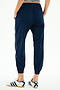 A person models the SPLITS59 Megan Woven Nylon Jogger w/ Piping in Indigo/Creme, featuring white side piping, paired with white Adidas sneakers, standing on a plain white background and photographed from the back.