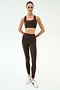 A person stands facing forward in the SPLITS59 Lexi Rigor Bra - Dark Chocolate/Black with matching leggings and white sneakers—ideal gym wear—against a plain white background.