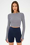 A woman wears the SPLITS59 Louise Rib Long Sleeve Crop in White/Indigo Stripe with high-waisted navy blue bike shorts, standing against a plain white background.
