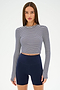 A woman wears the SPLITS59 Louise Rib Long Sleeve Crop in White/Indigo Stripe with high-waisted navy blue bike shorts, standing against a plain white background.