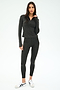 A woman stands in a studio wearing the SPLITS59 Stevie Active Rib Half Zip Waist Length top in Heather Graphite, paired with matching leggings and white sneakers, with a neutral expression.