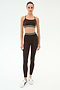 A woman stands against a plain background wearing the SPLITS59 Bailey High Waist Active Rib 7/8 leggings in Heather Dark Chocolate, paired with a matching rib sports bra and white sneakers—ideal for gym workouts.