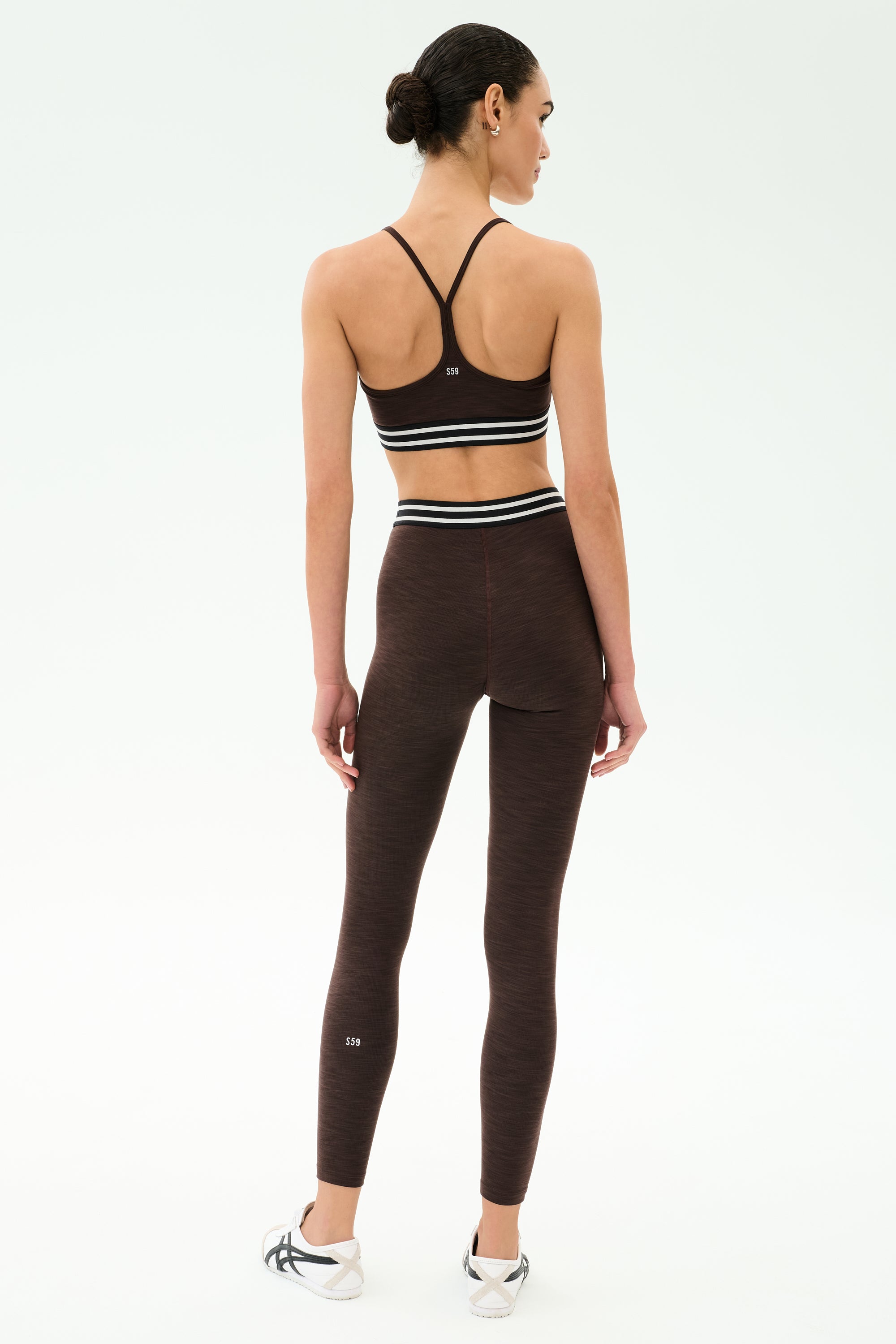 A person stands with their back to the camera, wearing the SPLITS59 Cali Active Rib Bra in Heather Dark Chocolate with matching high-waisted leggings, set against a plain white background.