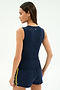 A woman stands with her back to the camera, wearing the SPLITS59 Carter Airweight Lite Tank in Indigo, paired with navy shorts featuring yellow side stripes, all made from a comfy nylon-spandex blend.