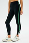 A person wearing SPLITS59's Layla Airweight High Waist 7/8 in Black/Arugula, paired with white sneakers, stands against a plain background.