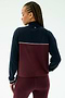 A person with braided hair is shown from the back wearing the SPLITS59 Millie Airweight Half Zip in Dark Cherry/Indigo, standing against a plain light background.