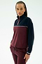A woman wears the SPLITS59 Millie Airweight Half Zip in Dark Cherry/Indigo, a comfortable nylon-spandex blend track suit, standing with one hand in her pocket and looking at the camera against a plain white background.
