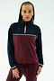 A woman wears the SPLITS59 Millie Airweight Half Zip in Dark Cherry/Indigo with matching pants, made from a nylon-spandex blend, standing against a plain light background.