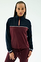 A woman wears the SPLITS59 Millie Airweight Half Zip in Dark Cherry/Indigo with matching pants, made from a nylon-spandex blend, standing against a plain light background.