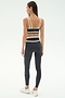 A woman faces away, wearing SPLITS59's Mason High Waist Rigor Full Length leggings in Graphite/White with a matching sports bra and white sneakers, set against a plain light background.