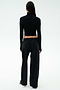 A person faces away, wearing SPLITS59's Brynn Airweight Pant in black, paired with a black spandex long-sleeve turtleneck and white sneakers against a plain light background.