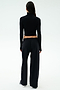 A person faces away, wearing SPLITS59's Brynn Airweight Pant in black, paired with a black spandex long-sleeve turtleneck and white sneakers against a plain light background.