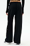 Shown from the back against a plain white background, a person wears SPLITS59 Brynn Airweight Pant in black with a black long-sleeve spandex top and white shoes.