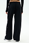 Shown from the back against a plain white background, a person wears SPLITS59 Brynn Airweight Pant in black with a black long-sleeve spandex top and white shoes.