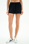 Model wears SPLITS59 Ella Airweight Track Short in Black/White, made of nylon spandex, and white sneakers, standing against a white background, visible from midriff to feet.