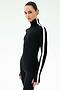 A woman stands against a plain light background wearing the SPLITS59 Jackson Rib Full Length Turtleneck in Black/White with a fitted design and white vertical sleeve stripe.